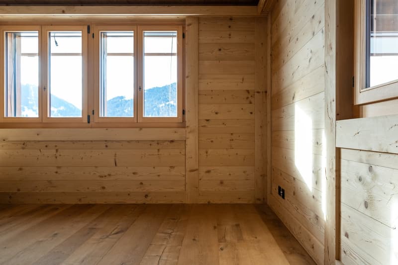 wooden walls and floors, three windows, no furniture