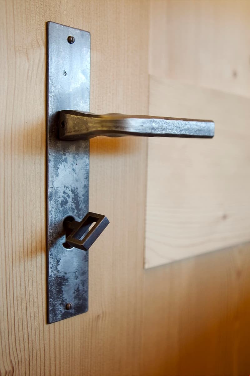 Metallic handle with rectangular and square shapes attached to a wooden door