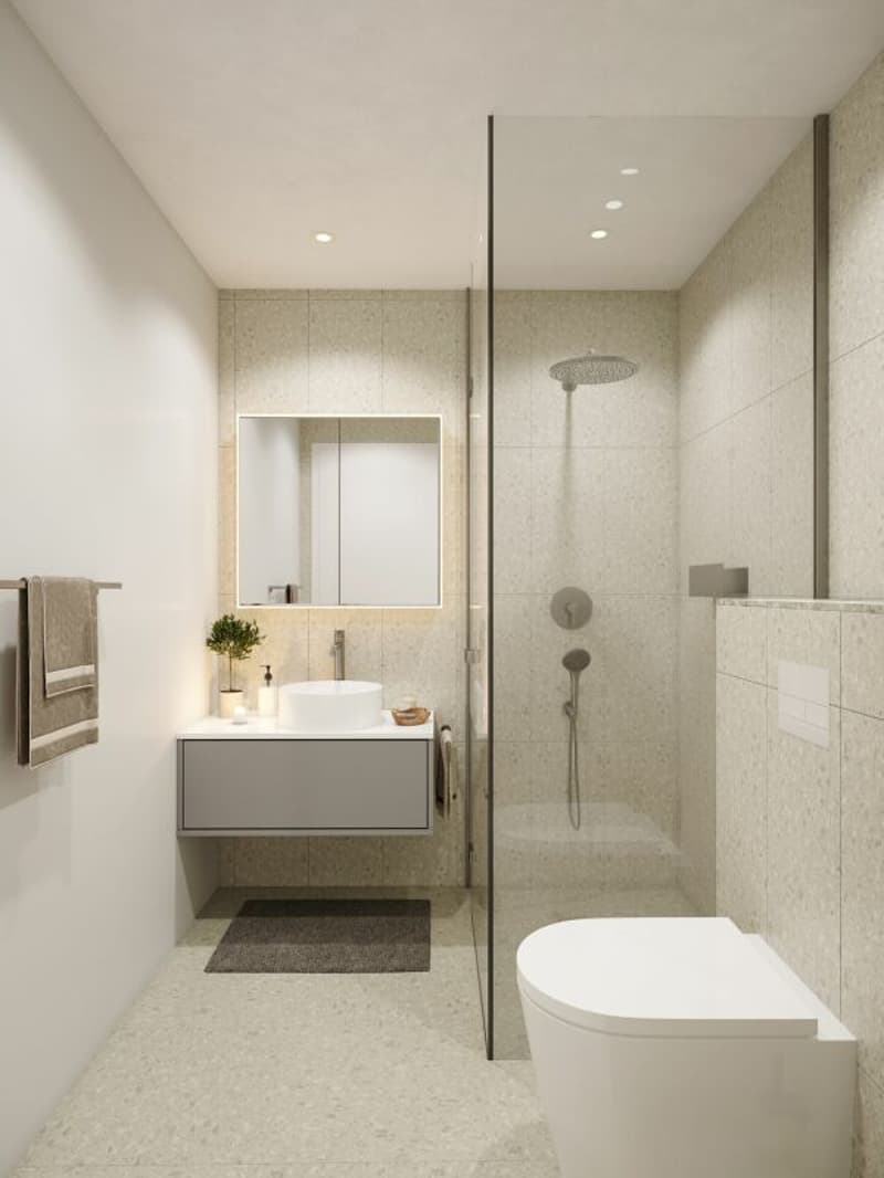 Die zwei Badezimmer sind identisch ausgestattet und verfügen über Toilette, Dusche und Waschbecken mit Unterbaumöbel. Das Farbkonzept ist harmonisch abgestimmt.
