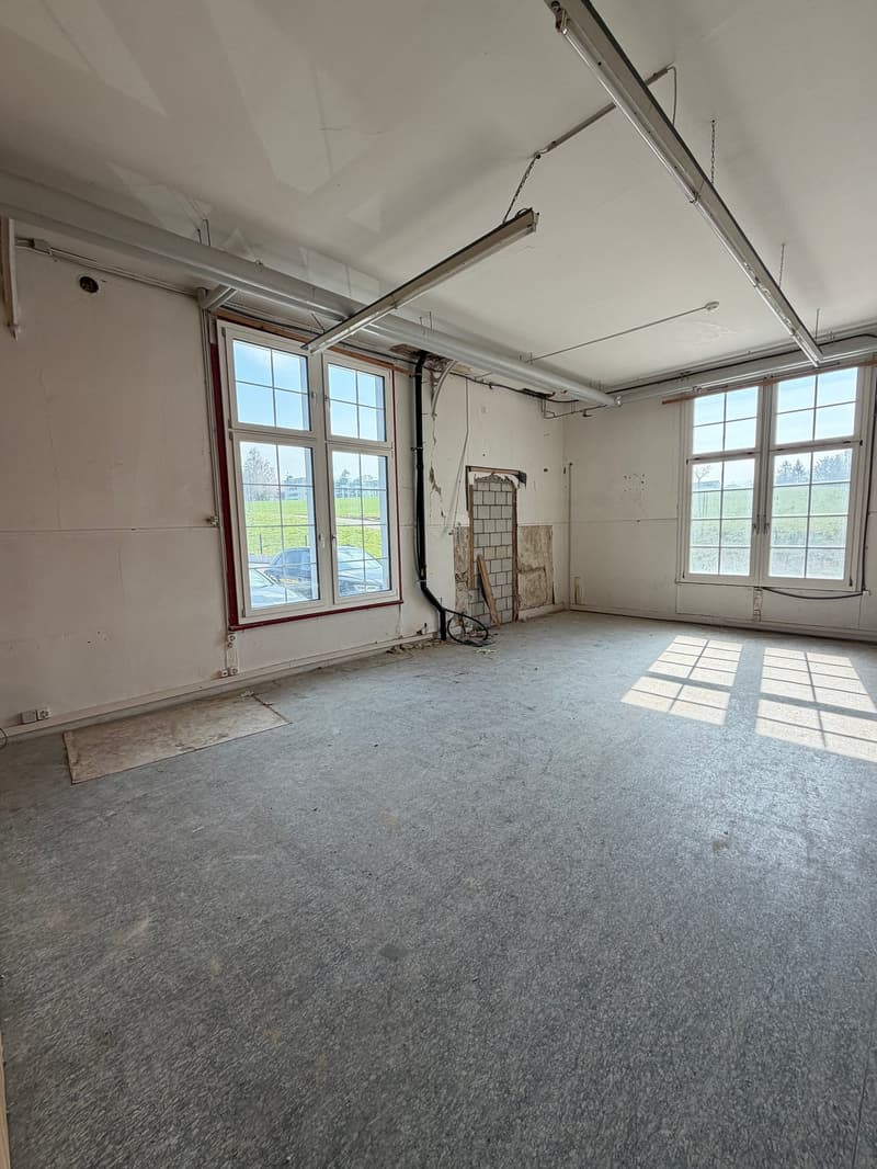 empty room, white walls, gray floor, two windows, pipes on ceiling