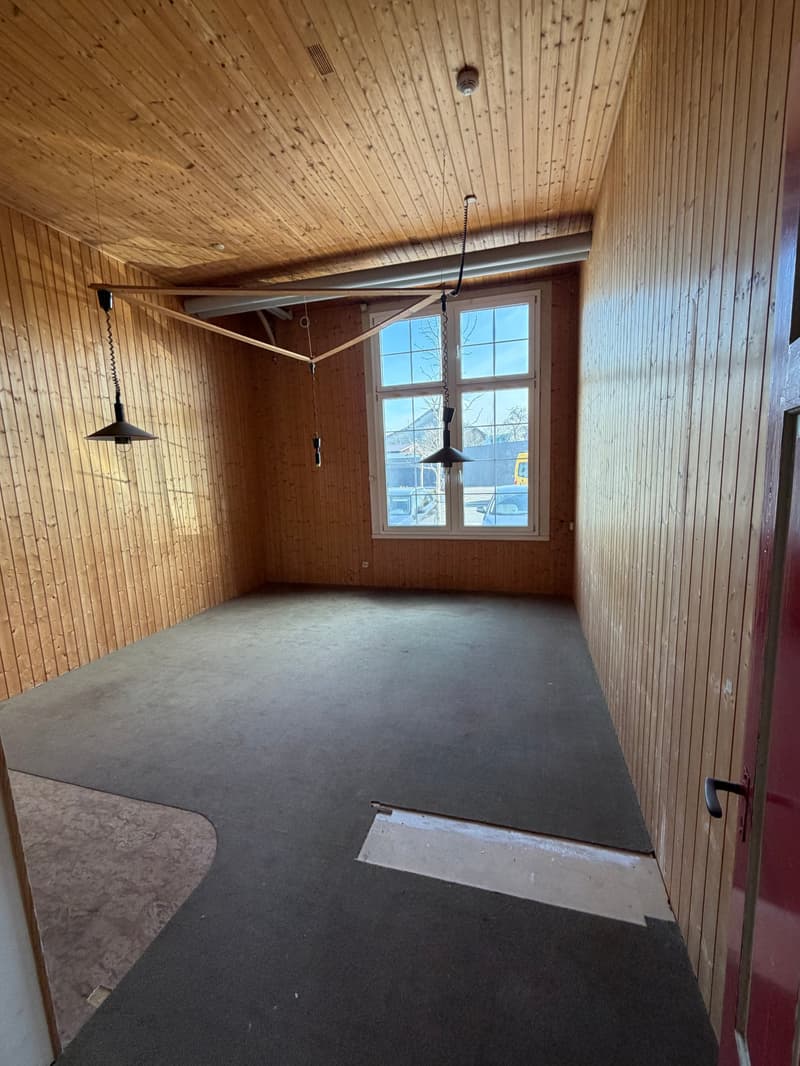 empty room, wooden walls, carpeted floor, large window, two hanging lamps