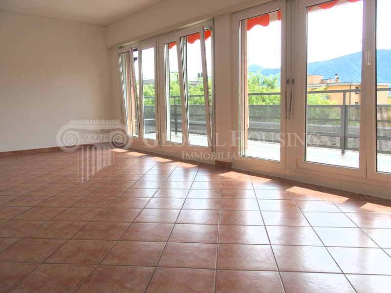 Large living room, glass sliding doors, balcony, tiled floor, panoramic view of the mountains