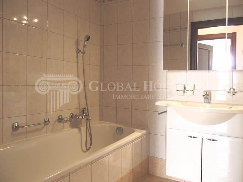 Bathtub, shower head, sink, mirror, tiled walls, cabinets, faucet