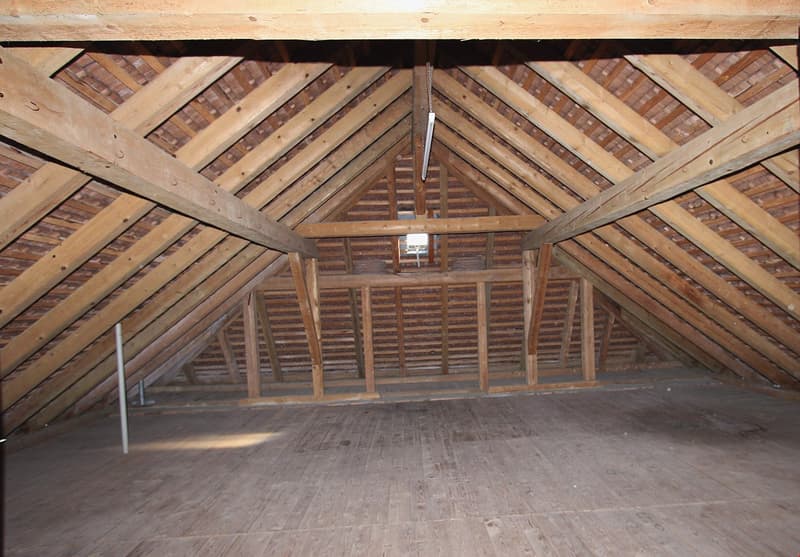 empty attic room with wooden beams and floor