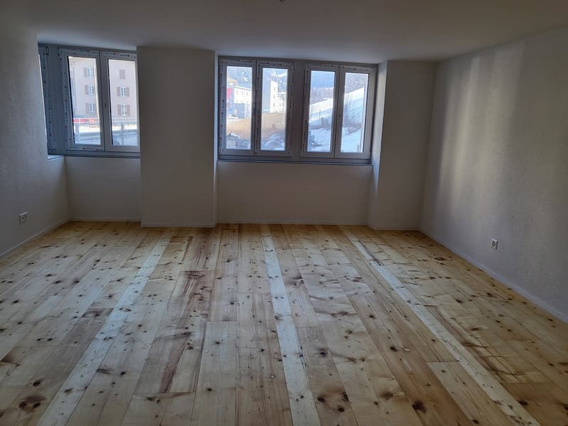 room with wooden floor, white walls, two windows, no furniture