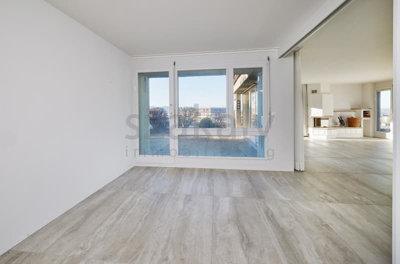 Modern living room with large windows, tile flooring, white walls, view of the outside