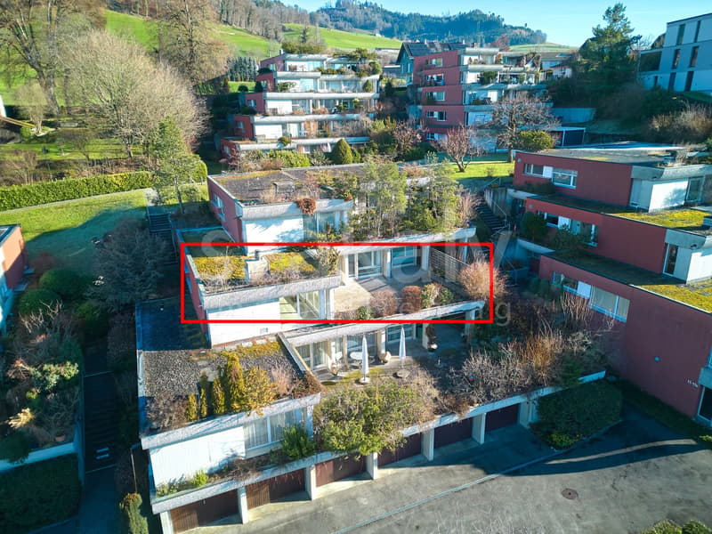 Multiple story residential building with rooftop terraces, located in a hillside neighborhood.