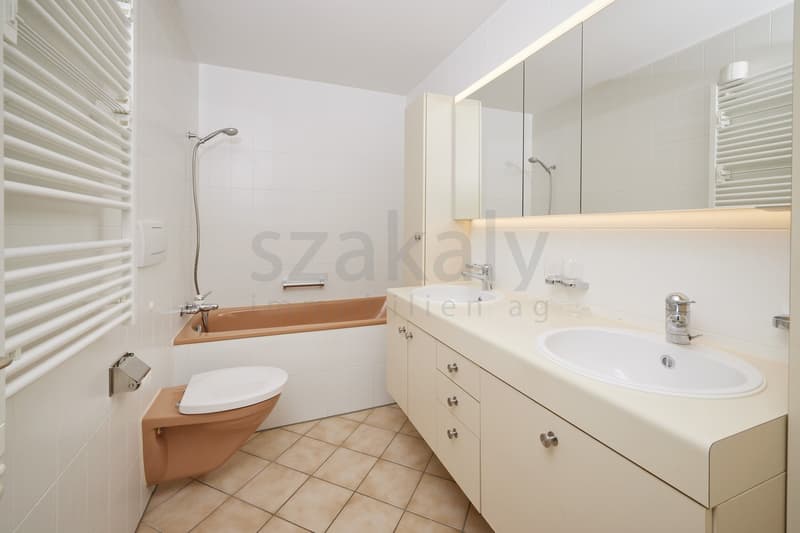 clean bathroom with tub and double sinks, white tiles and wooden floor