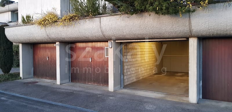 Building with three garages under a plant covered roof.