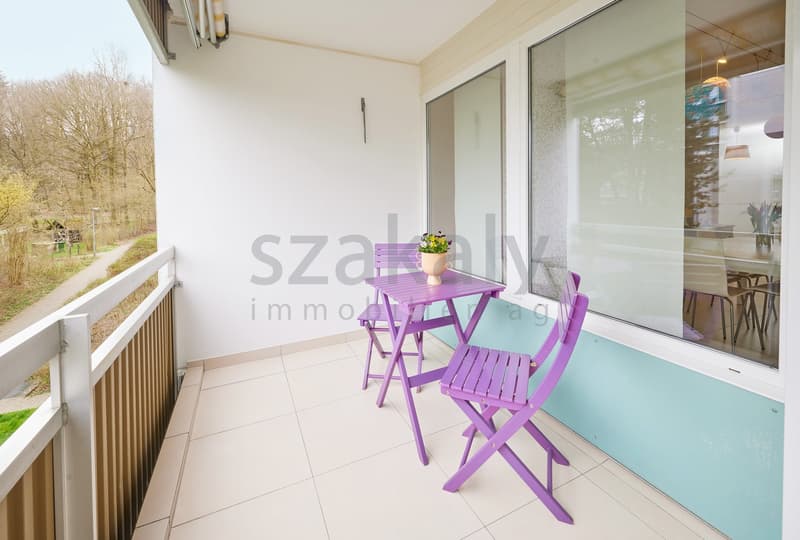 Balcony with white tiles, white railing, purple table and chairs, potted plant, glass door, view of trees