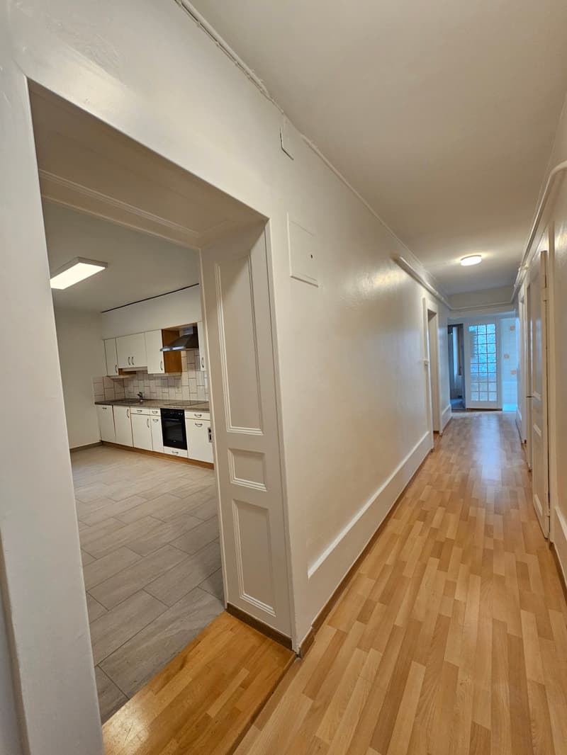Open hallway, kitchen, tiles in living room, cabinets, countertop, sink, stove, dishwasher, refrigerator, tiles in hallway.