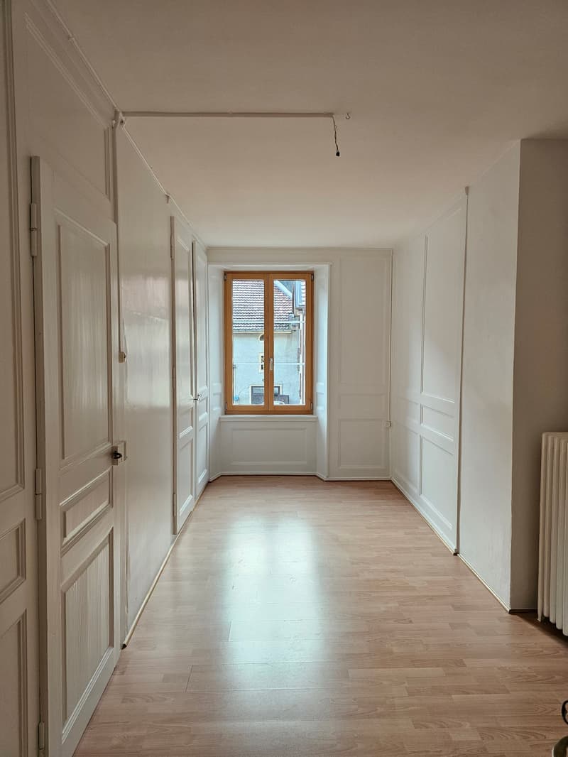Empty room, white walls, wooden flooring, windows, radiator, doors