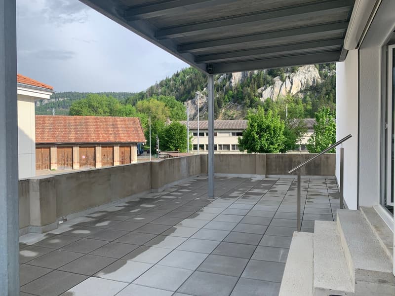 Tiled flooring, metal railings, concrete wall, glass door, mountains in the distance