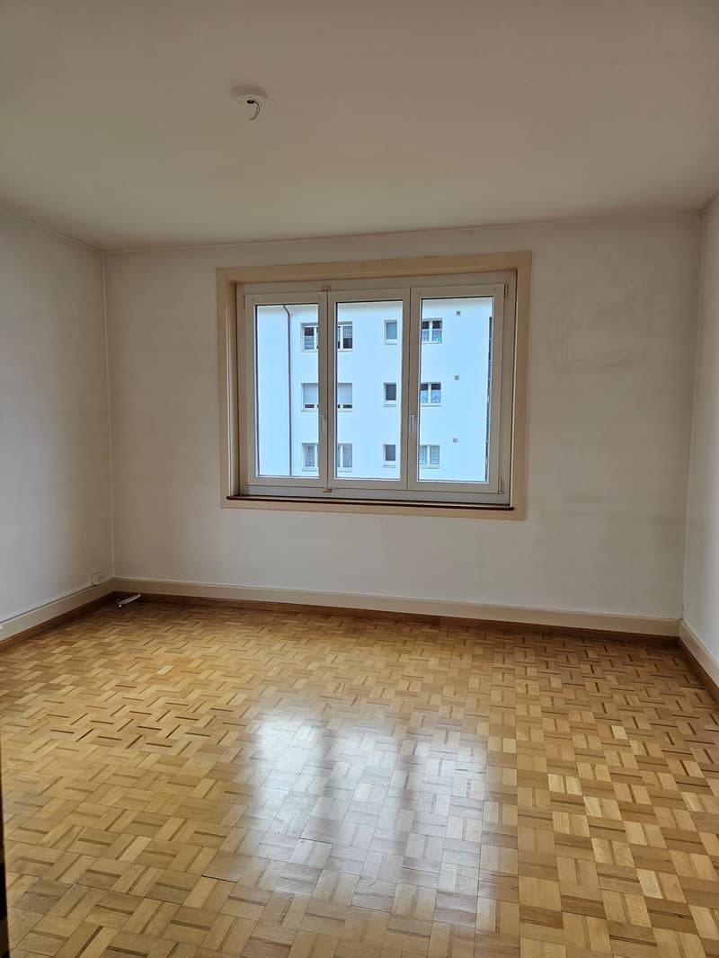 empty room with parquet flooring, large window, white walls