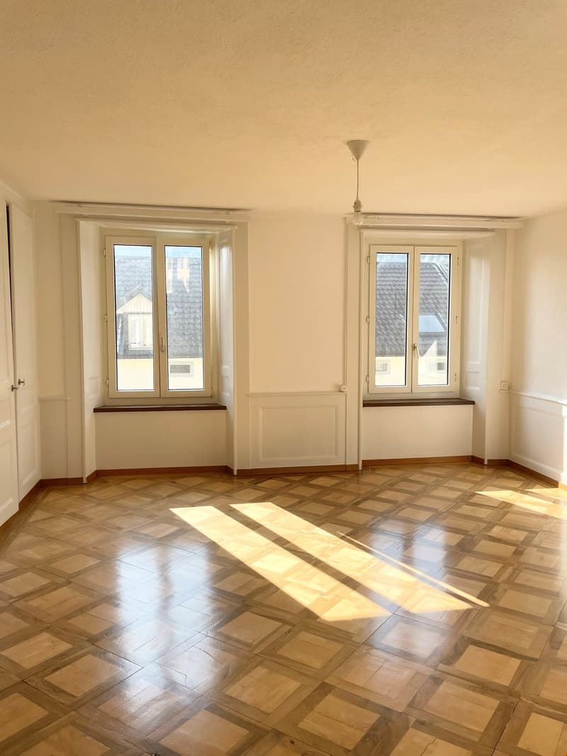 large room, parquet floor, white walls, large windows, radiator