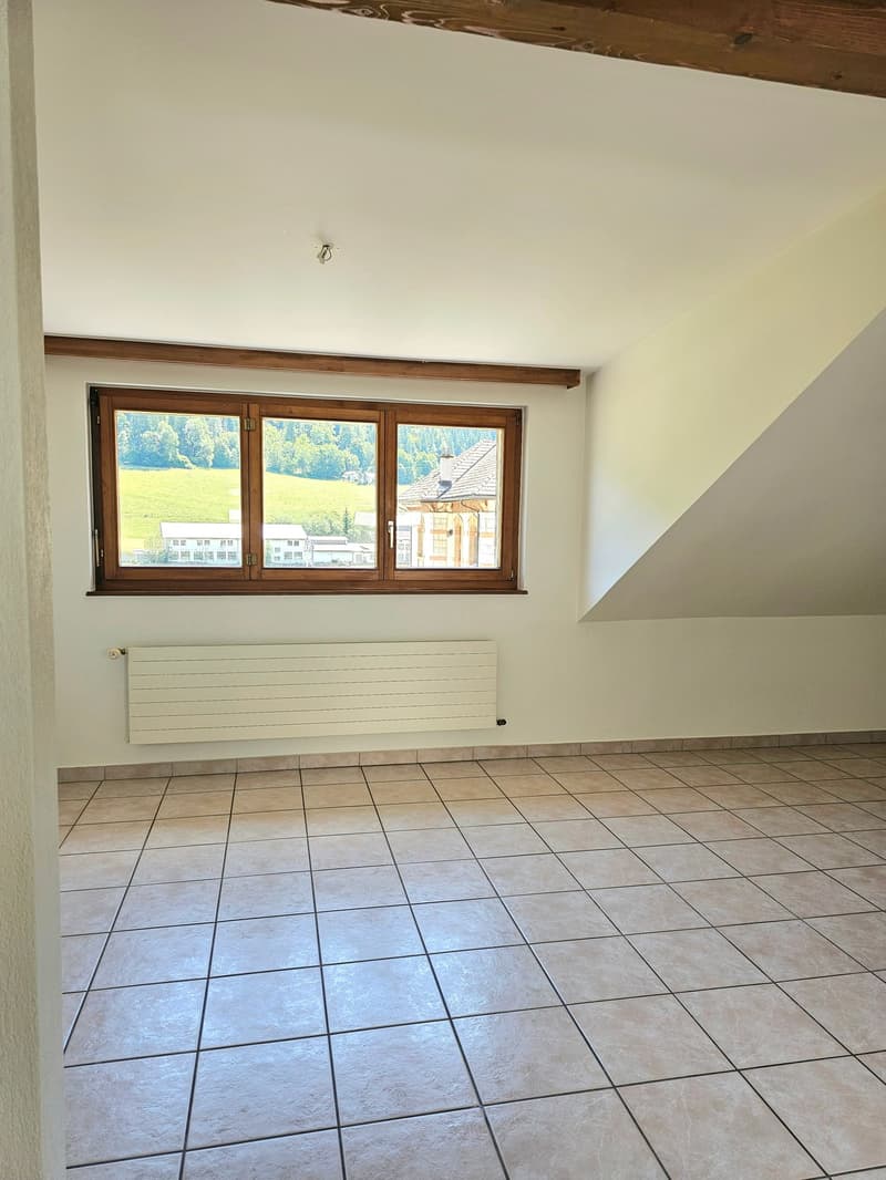 Spacious room with large windows overlooking a scenic outdoor view, hardwood ceiling beams, and tiled flooring.