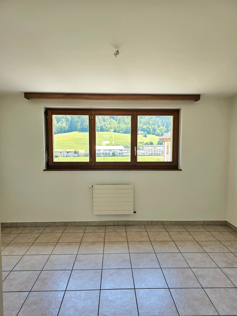Large windows with a scenic view of the countryside, tiled floor, and a radiator on the wall.