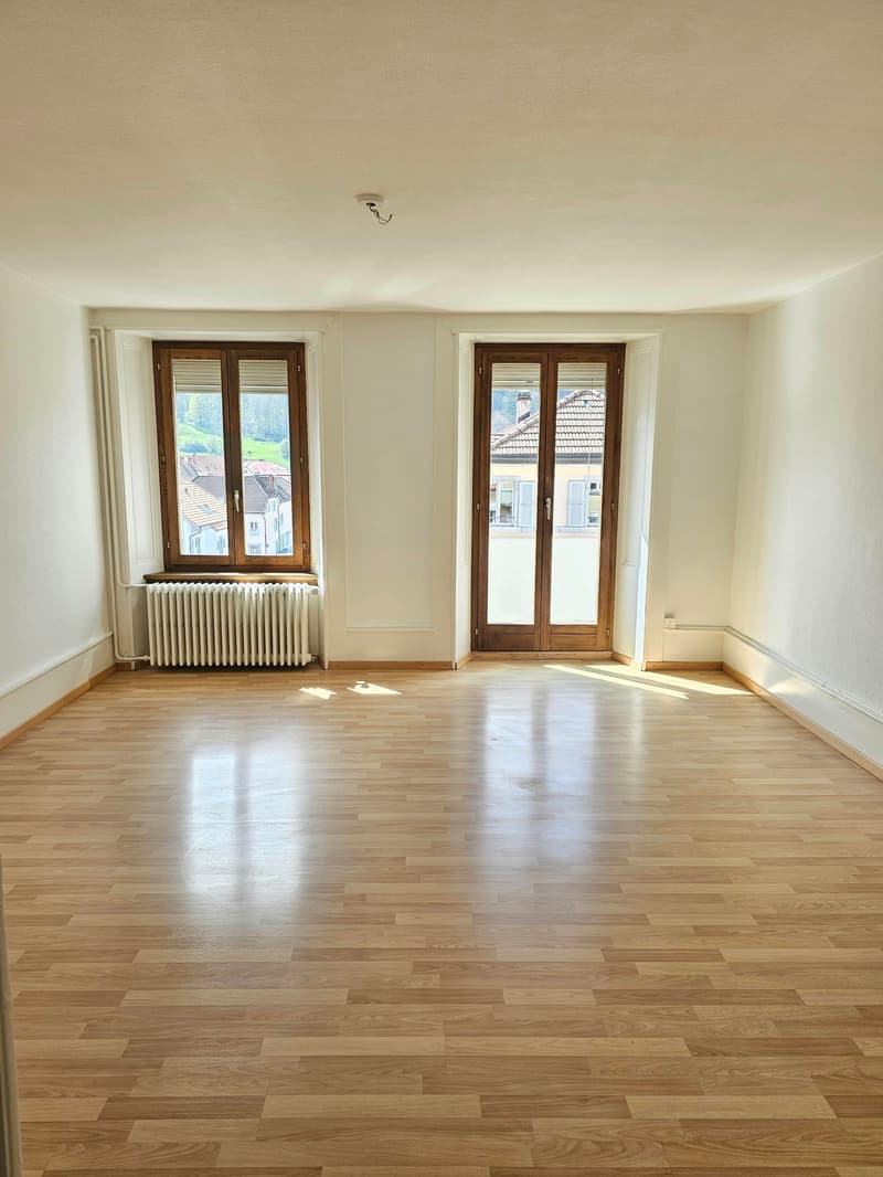 empty room, wooden floor, white walls, two windows, wooden doors, radiator