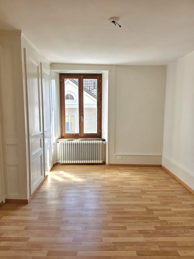 empty room, wooden floor, white walls, large window, white radiator