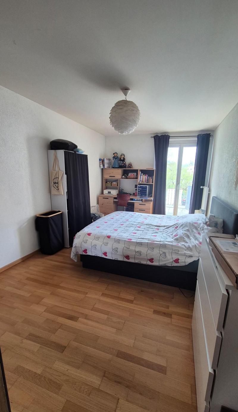 Bedroom with bed, desk, chair, cabinet, trash bin, lamp, and balcony