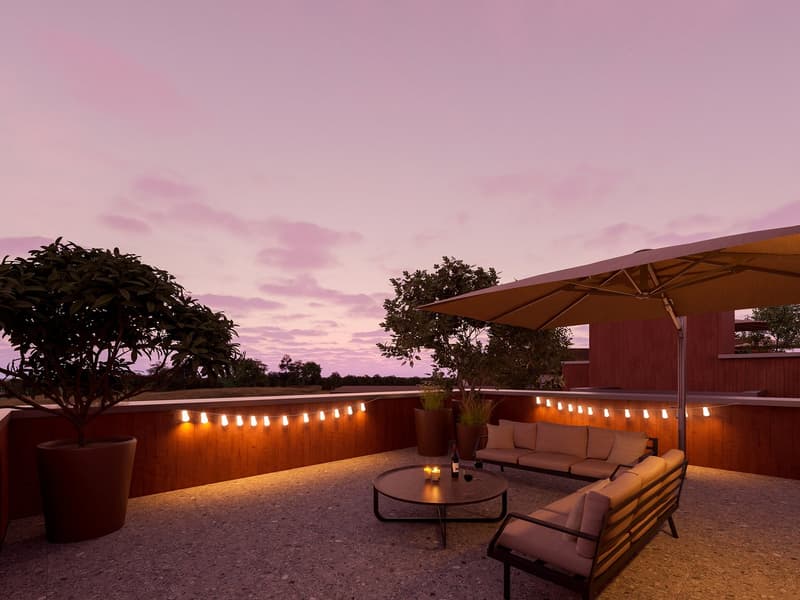 Outdoor seating area with a table, umbrella, and string lights, surrounded by potted plants, with a view of the sunset