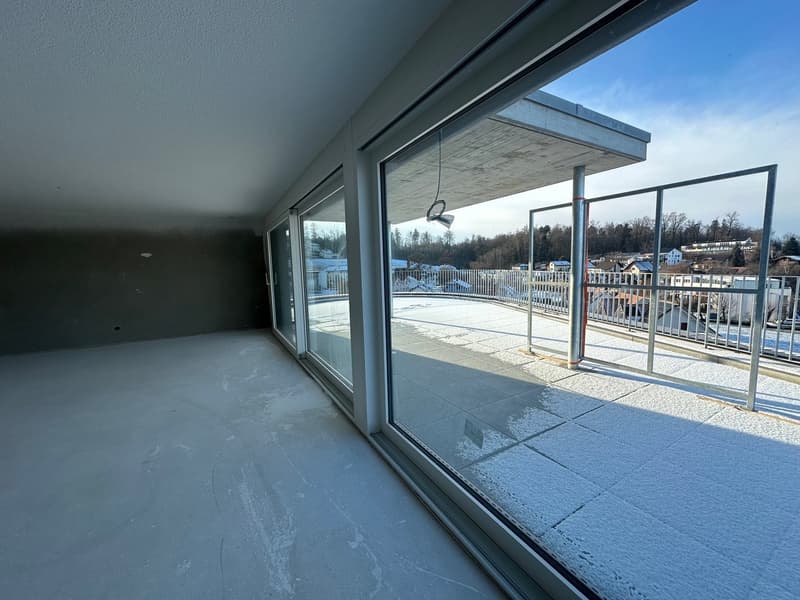Balcony with empty room and window overlooking a cityscape