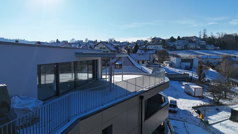 Modern house with a balcony, metal railings, snow-covered surroundings