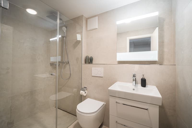modern bathroom with walk-in shower, white toilet, white vanity with sink, beige tiles, white mirror