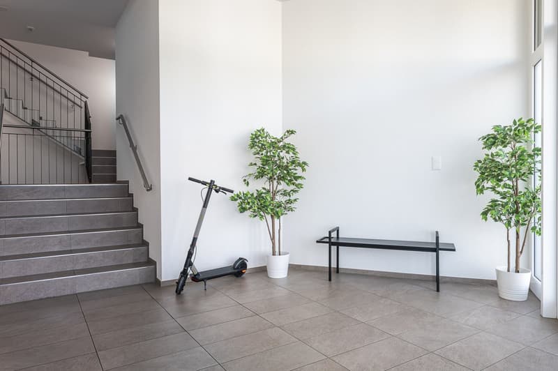 white walls, tiled floor, staircase, scooter, bench, plants
