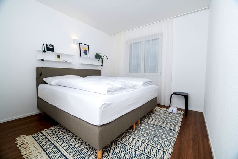 bed, pillows, rug, shelves, lamps, window, small stool