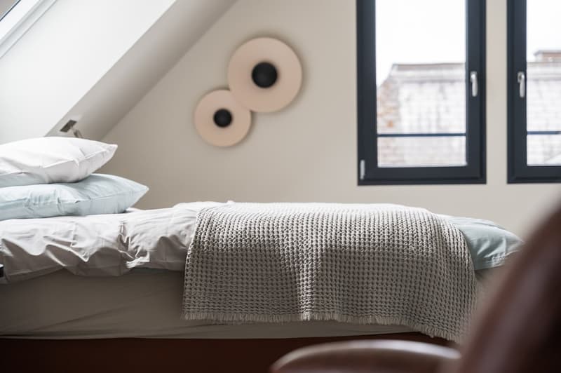 Bedroom: twin bed, knitted blanket, pillows, 2 lamps, 2 windows