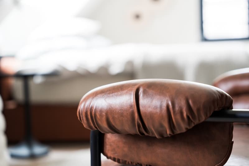 leather chair, brown, large, modern design, beside a bed, dark brown nightstand