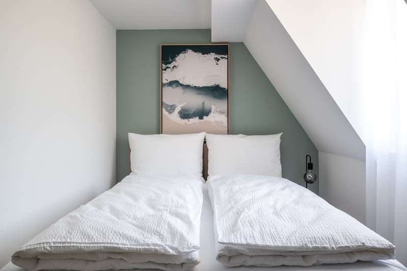 Two single beds, white bedding, green wall, painting, lamp