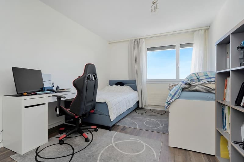 Two beds, single bed and trundle bed, desk with gaming chair, carpet, monitor, books