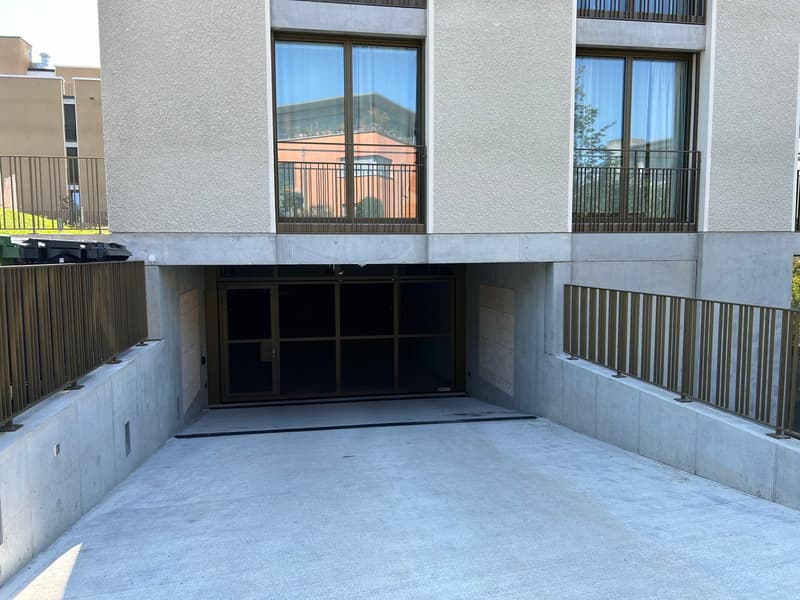 apartment building, concrete garage entrance, metal railings, 2 windows