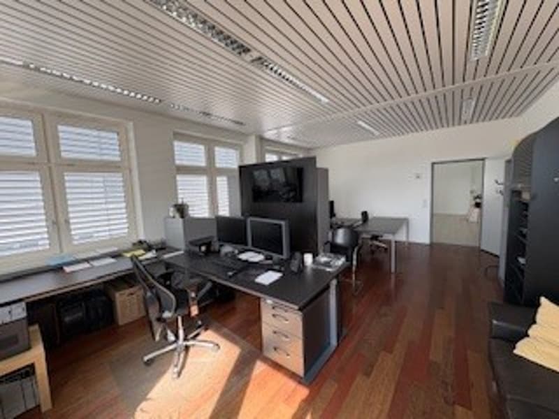 modern office, large windows, wooden floor, black desk, computer, chairs, shelves