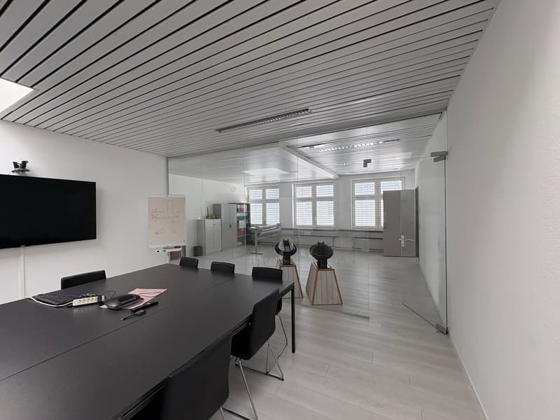 conference room with a long table, black chairs, whiteboard, TV, keyboard, mouse, and other office equipment