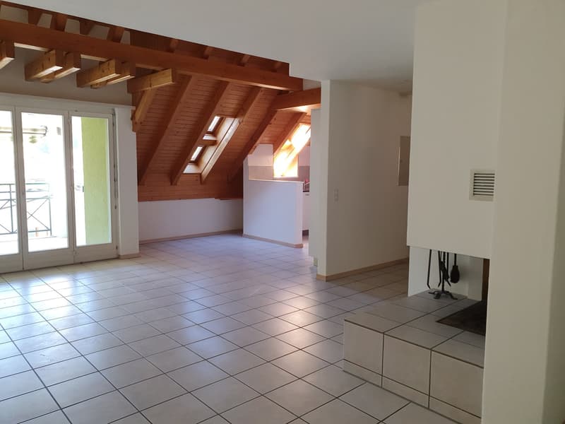 large living room with vaulted ceiling, wooden beams, fireplace, white tile flooring, sliding glass door, windows with balcony