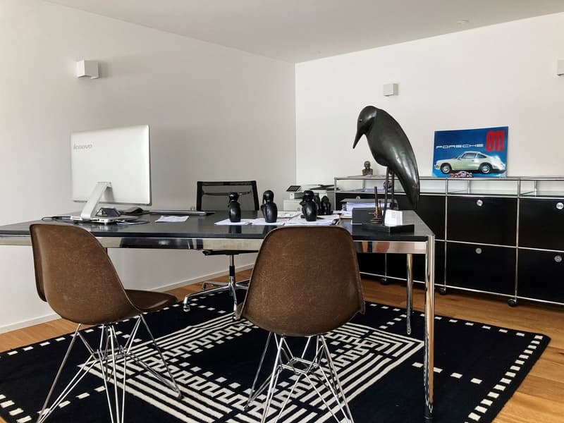 modern office setup with a desk, two office chairs, computer monitor, office cabinet, carpet, figurines, wall mounted speakers, a Porsche poster