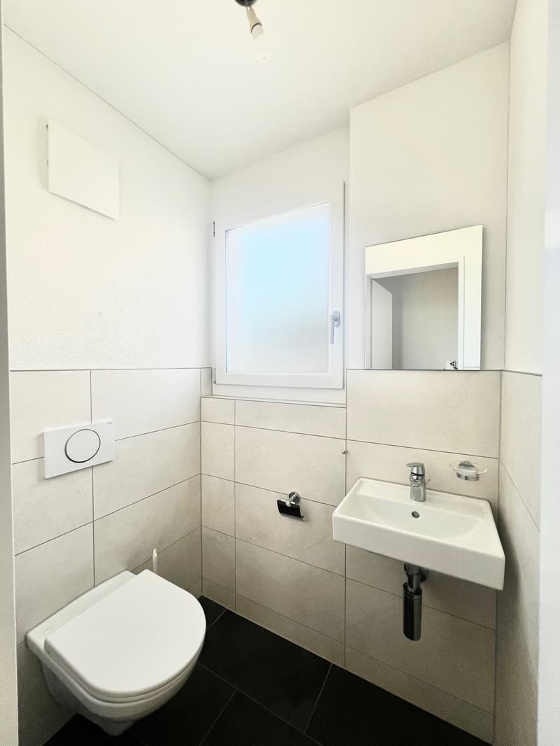 Bathroom with white tiles, white toilet, white sink, mirror, window