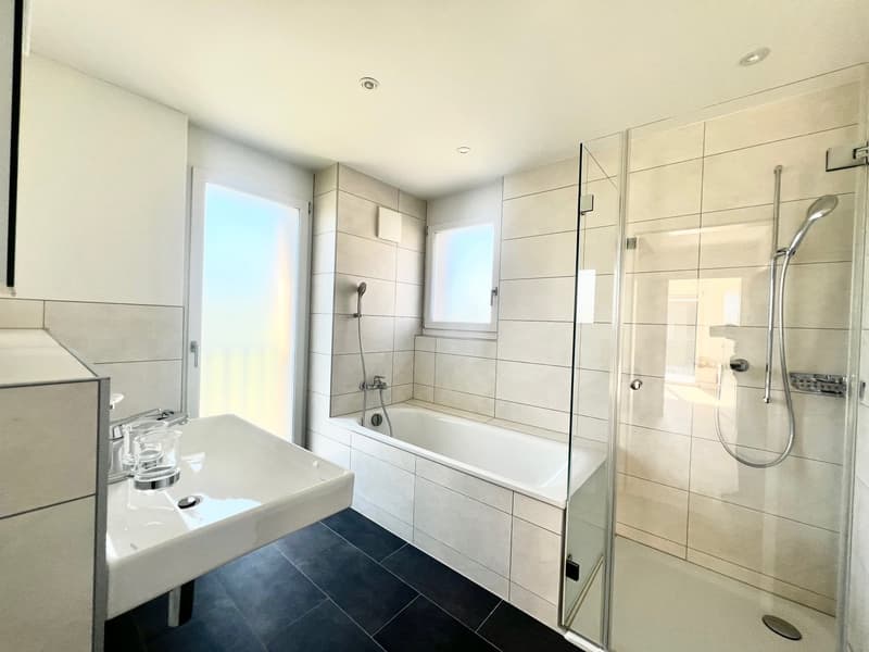 modern bathroom with white tiles, bathtub, shower, sink, and glass door
