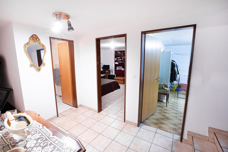 A room with tiled floor, wooden doors, a mirror, and a table with a bowl of items