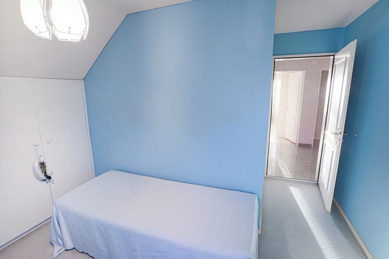 small bedroom with bed, blue walls, white wardrobe, open door