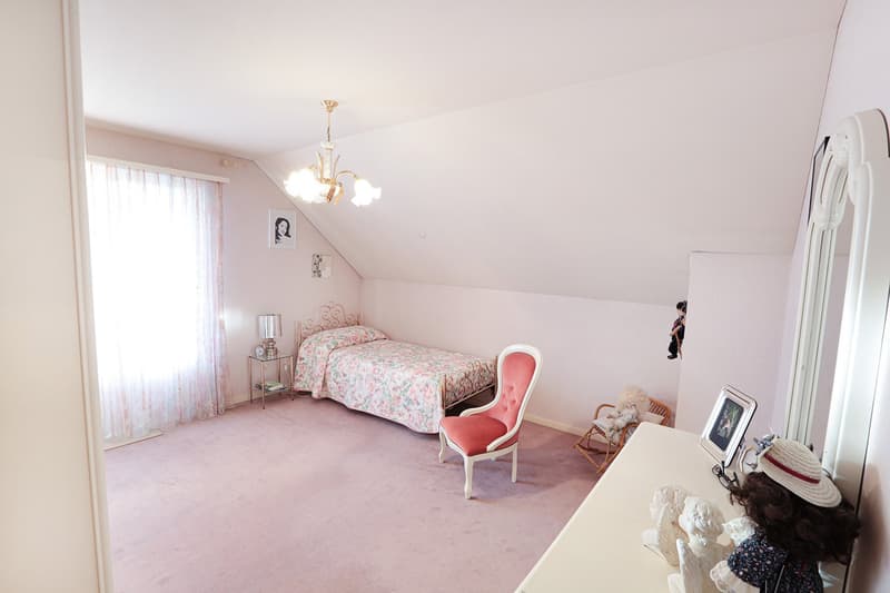 bedroom with bed, chair, mirror, picture frames, lamp, doll, carpet
