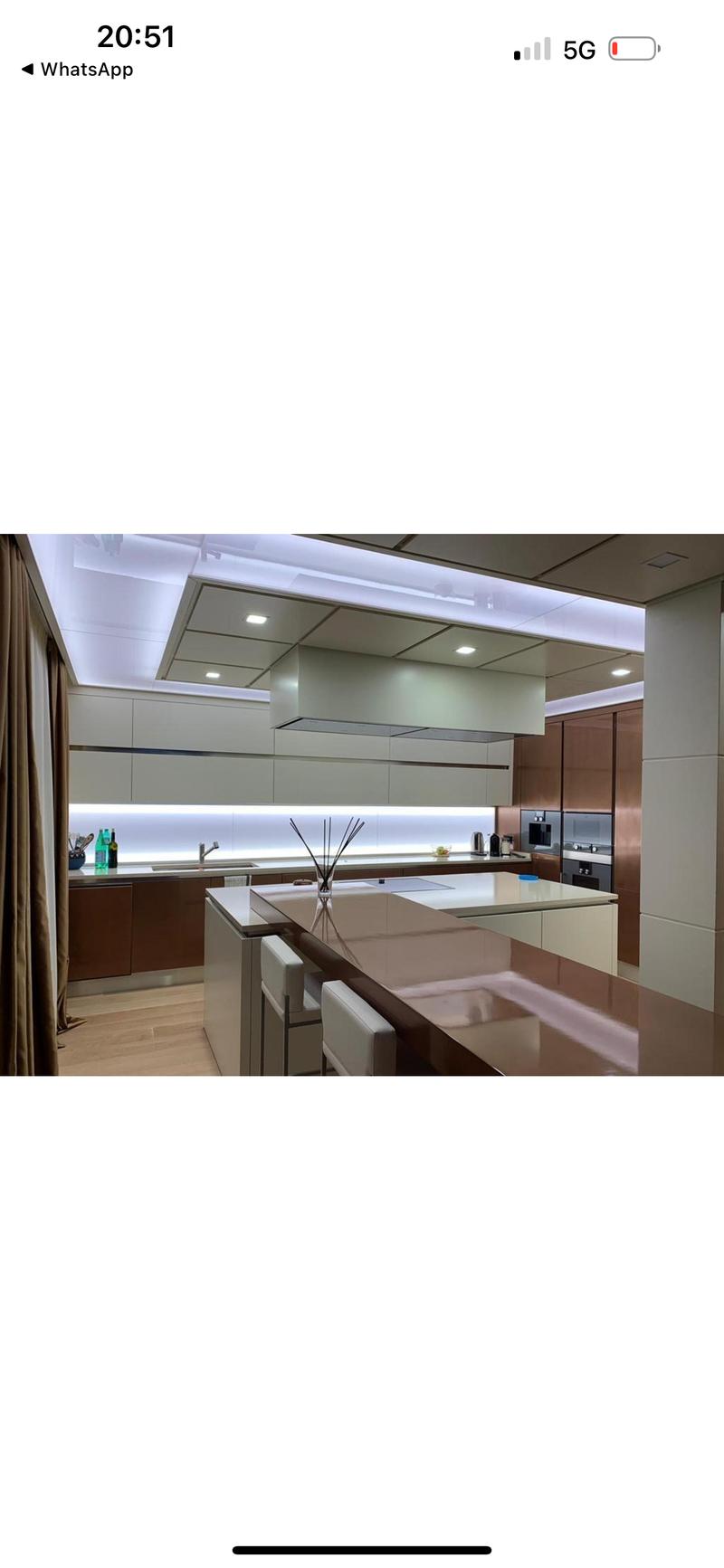 Modern, high-end kitchen with sleek gray cabinets, stainless steel appliances, and a large central island with a built-in dishwasher.