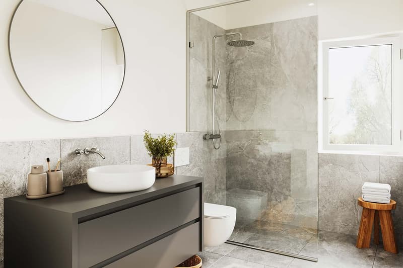 Modern bathroom with a glass shower enclosure, a white sink, a wooden stool, and a round mirror on the wall.