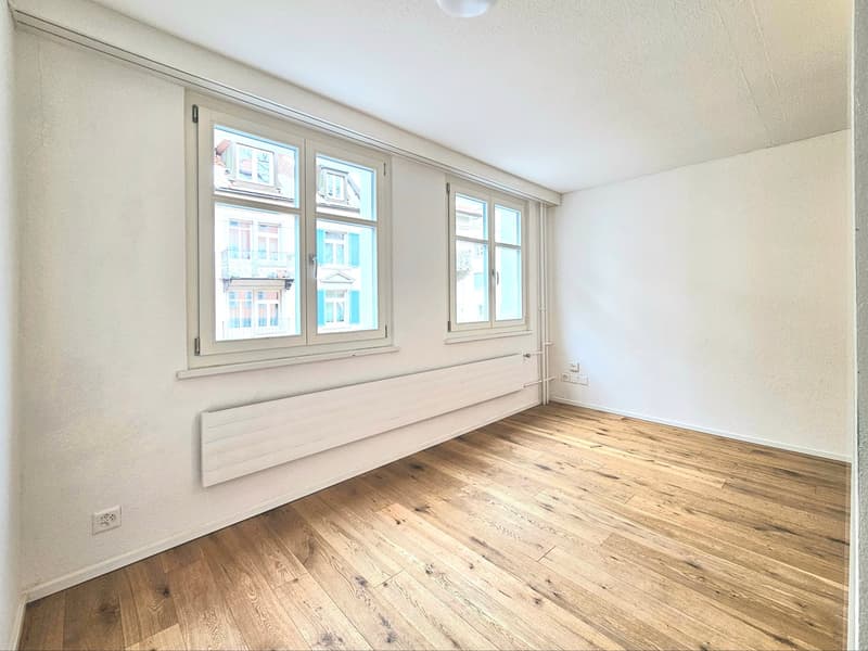 empty room, wooden floor, white walls, two windows, white radiator
