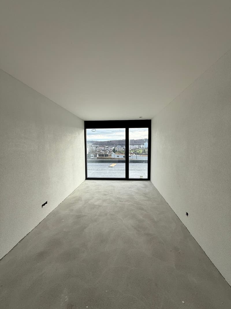 Large room with glass door and view of a cityscape