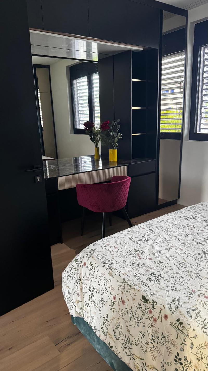Wooden floor, double bed, floral bedspread, large mirror, dressing table, velvet chair, flower vases