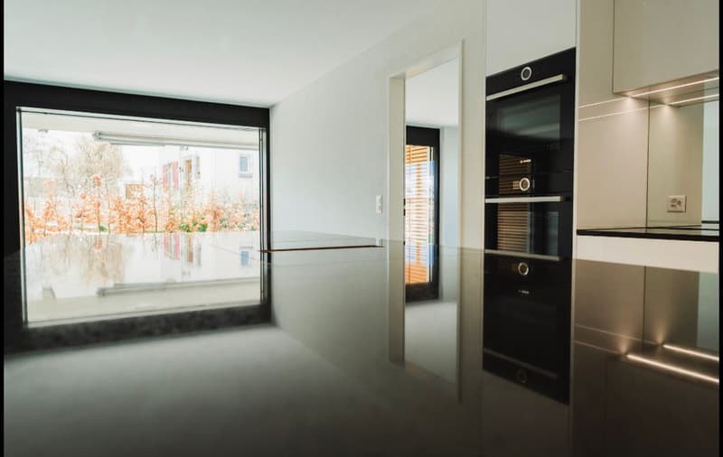 modern kitchen with large window, stainless steel appliances, white cabinets, black countertops